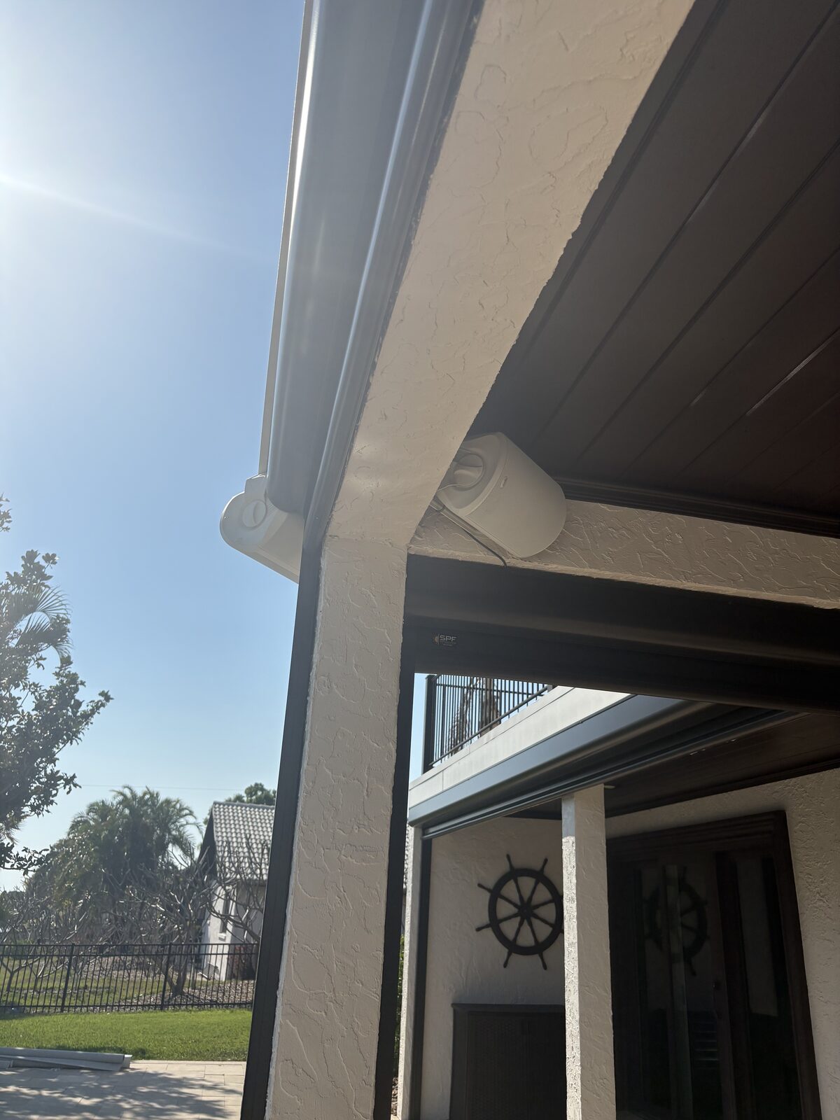 Weather-rated outdoor speaker mounted under a lanai soffit