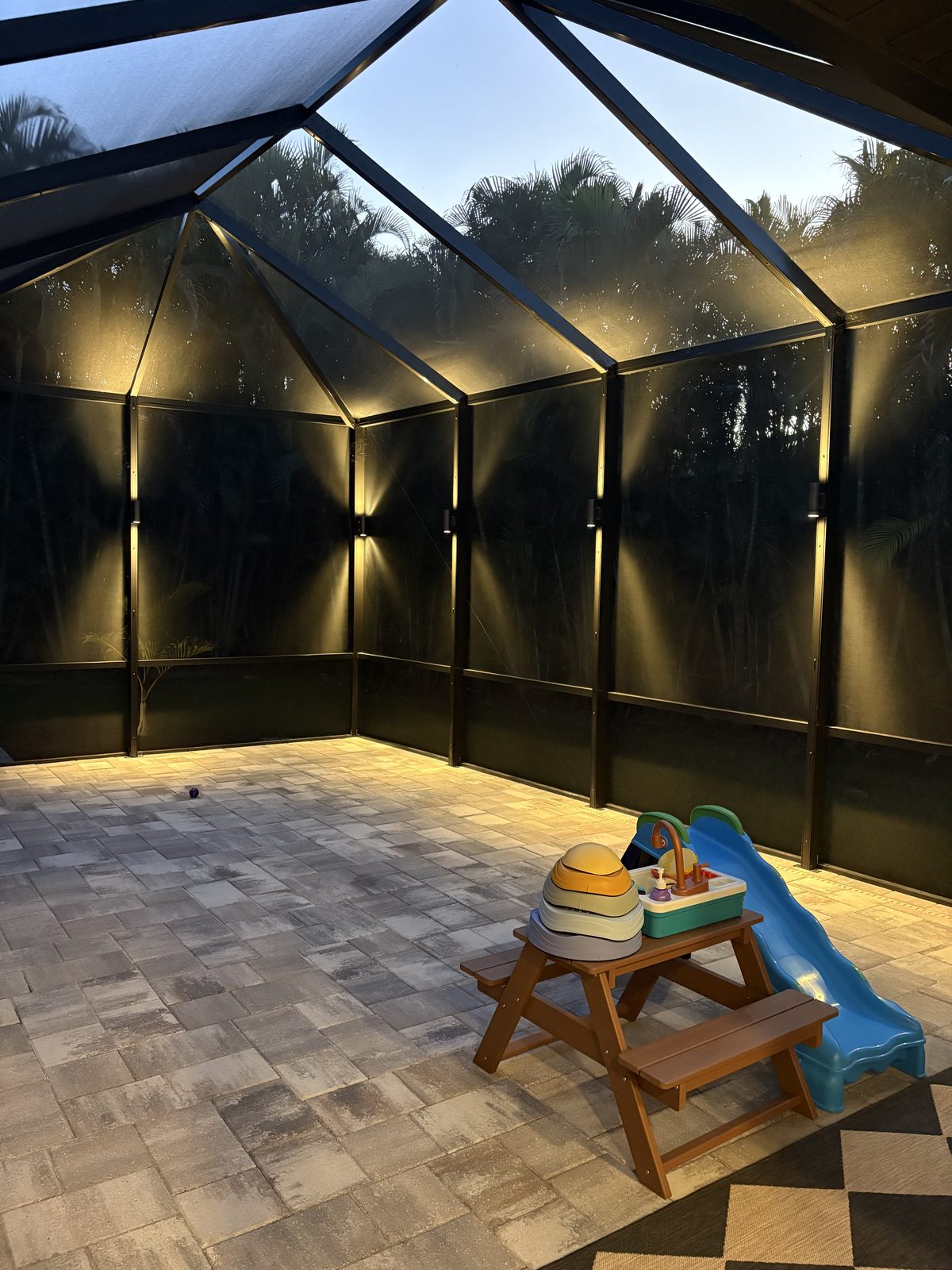 Pool cage lanai lit at night with warm LED lighting