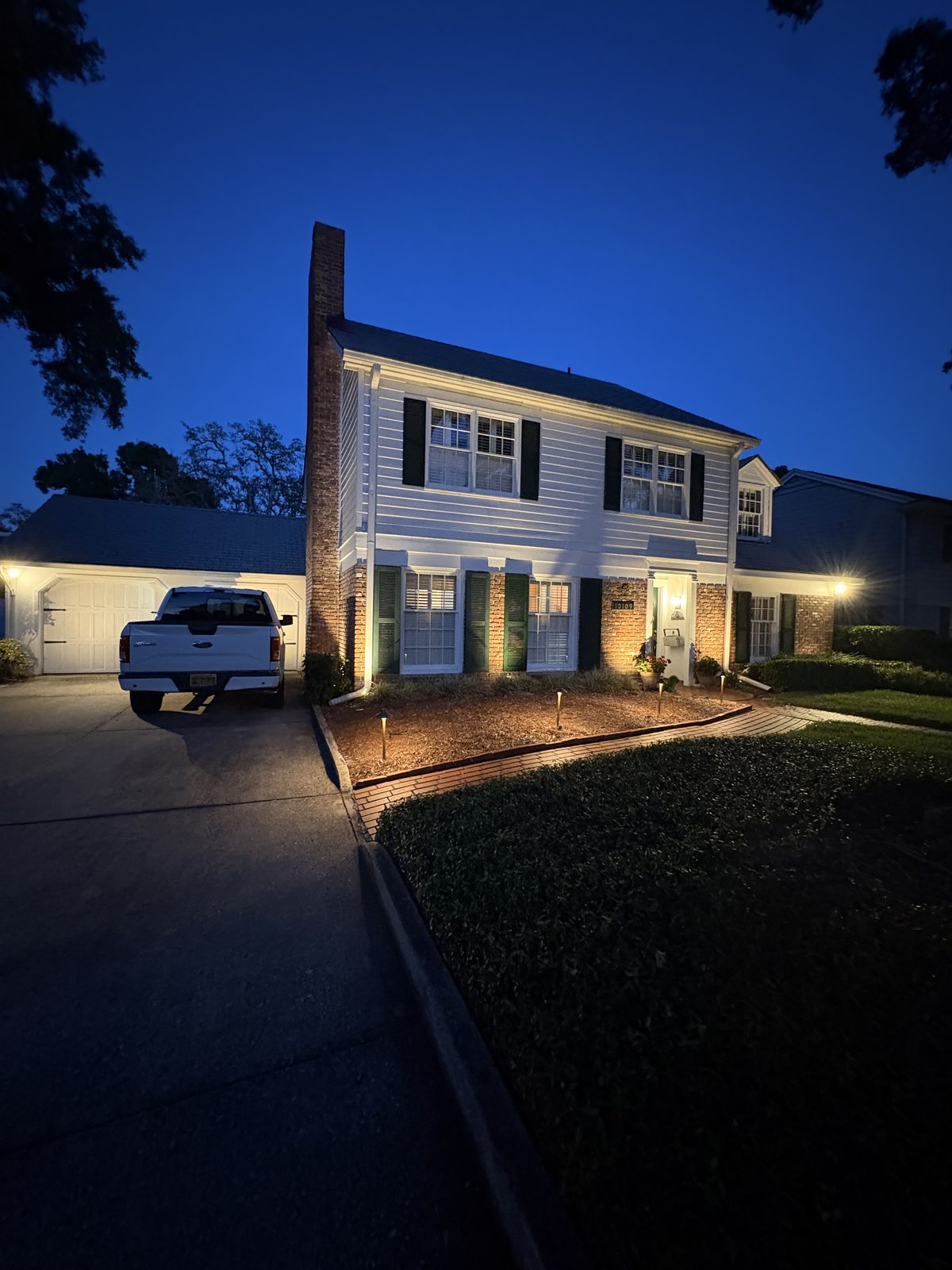 Two-story colonial home with facade uplighting and path lights