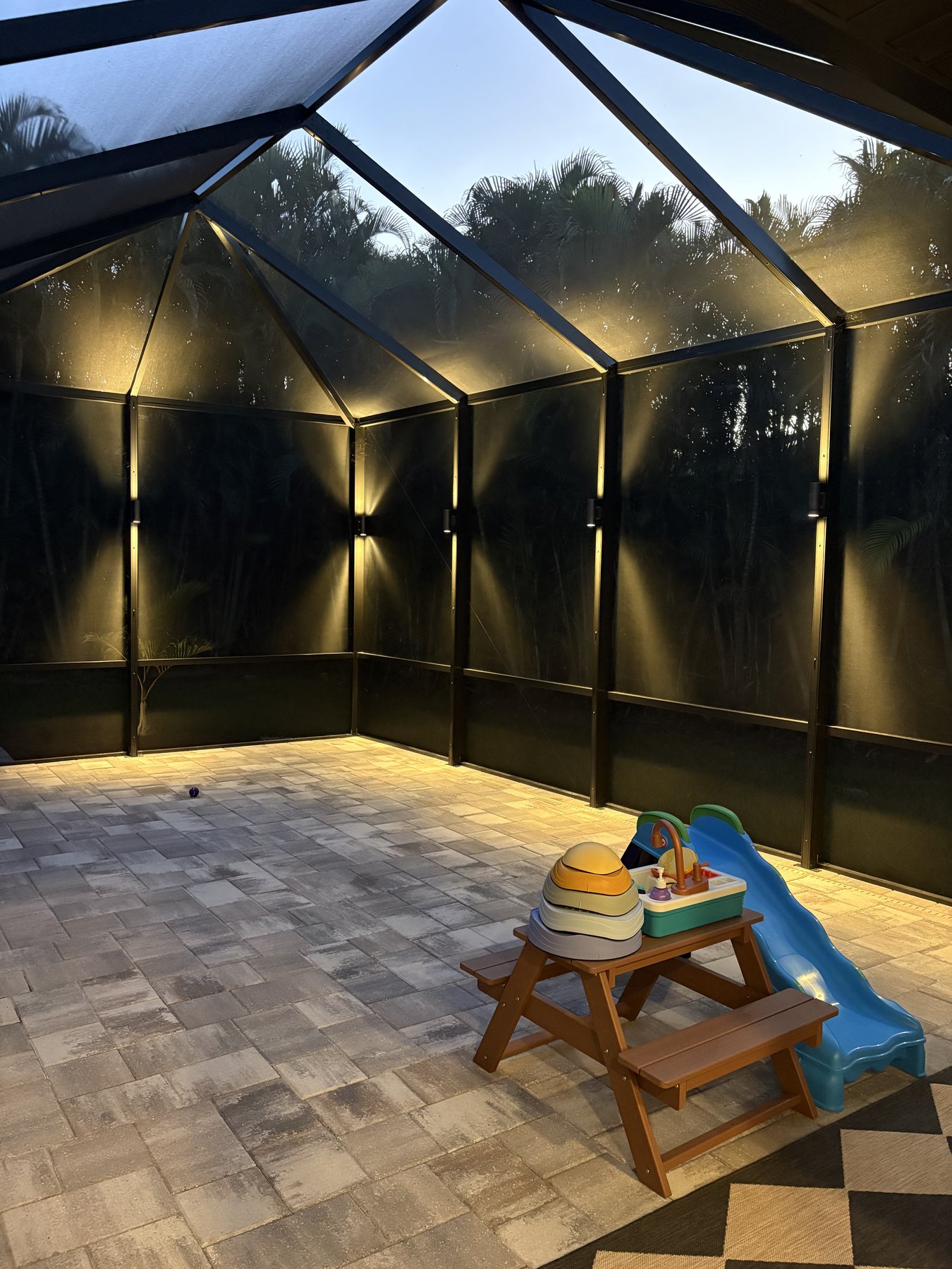 Screened lanai lit with warm landscape lighting in the evening