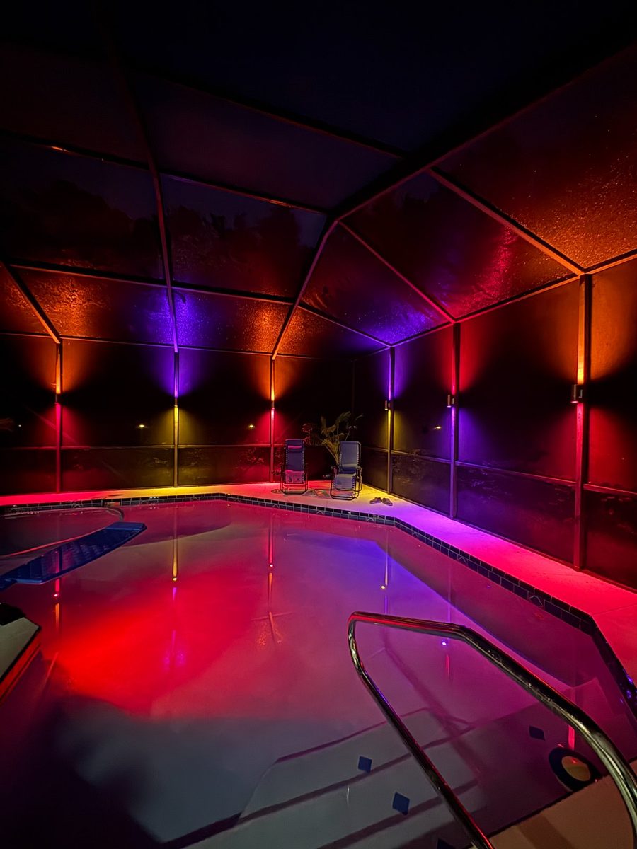 Pool cage at night with red and blue color sconces